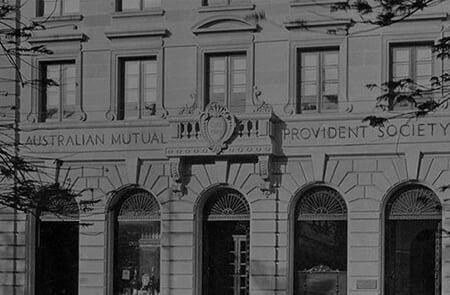 Historic black and white photograph showing the ornate stone facade of the Australian Mutual Provident Society building with carved lettering